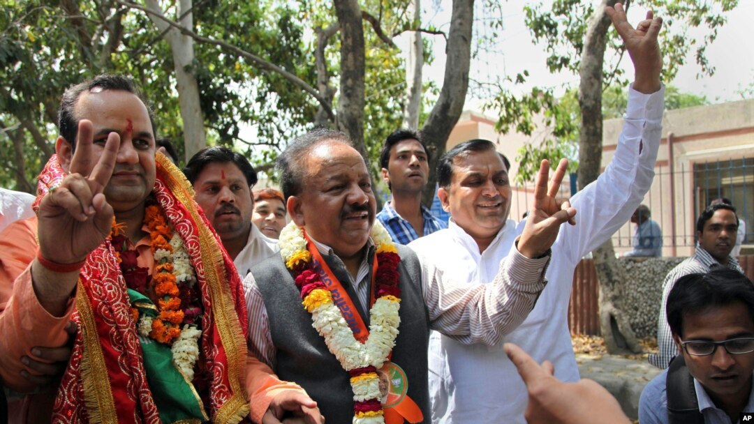 India main opposition Bharatiya Janata Party leader Harsh Vardhan, center, flashes a victory sign as he arrives with party nominee Mahesh Giri, left, to file Giri's nomination papers for the upcoming general election in New Delhi, March 20, 2014.