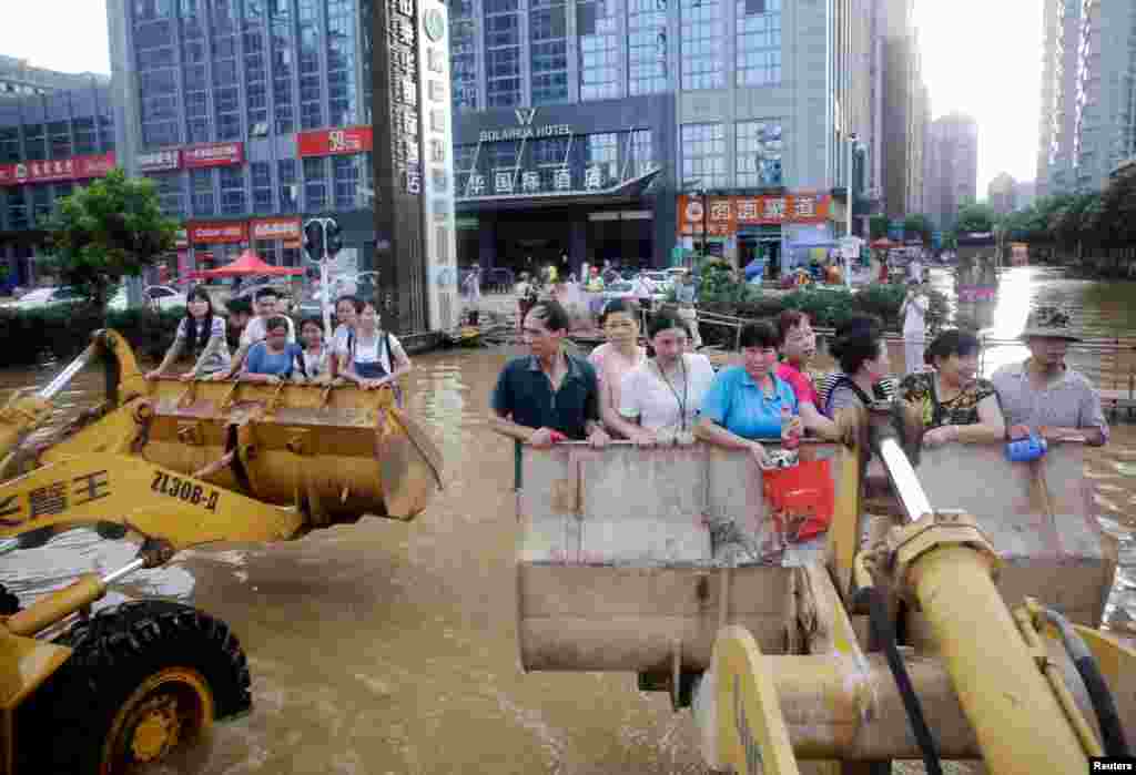 People use excavators as they make their way to work through floodwaters in Wuhan, Hubei province, China.