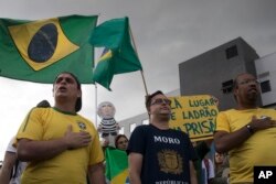 Manifestantes que apoyan la condena a prisión del expresidente Luiz Inacio Lula da Silva, cantan el himno nacional frente al Departamento de Policía de Curitiba, Brasil, donde se espera que el exmandatario se entregue. Abril 6 de 2018.