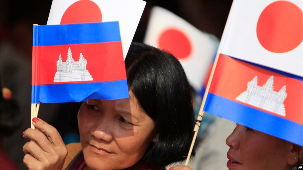 Cambodians hold Japan's flags and their national flags as they listen to Prime Minister Hun Sen's speech during an inauguration ceremony of a road funded by Japan for its official use at Kdey Takoy village, outside of Phnom Penh, Cambodia, Tuesday, March 13, 2018. (AP Photo/Heng Sinith)