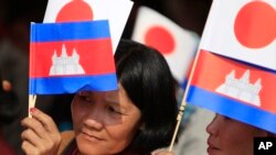 Cambodians hold Japan's flags and their national flags as they listen to Prime Minister Hun Sen's speech during an inauguration ceremony of a road funded by Japan for its official use at Kdey Takoy village, outside of Phnom Penh, Cambodia, Tuesday, March 13, 2018. (AP Photo/Heng Sinith) 