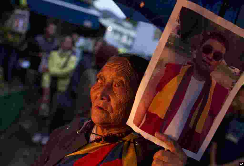 An exile Tibetan holds a portrait of Tsewang Norbu, 29, a Buddhist monk who died Monday after setting himself on fire in China's Sichuan province's Garze Tibetan Autonomous Prefecture during a candle light vigil in Dharmsala, India, August 15, 2011. (AP)