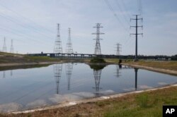 FILE - In this June 27, 2016, file photo, power lines tower over a coal ash pond from an abandoned coal fired power plant in Chesapeake, Virginia.