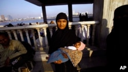 FILE - A Muslim woman holds her child and stands at the Haji Ali Dargah in Mumbai, India.