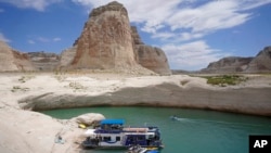 FILE - A houseboat rests in a cove at Lake Powell near Page, Ariz. This summer, the water levels hit a historic low amid a climate change-fueled megadrought engulfing the U.S. West, July 30, 2021.