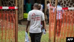 Des membres de l'équipe de Médecins Sans Frontières traversent une zone de sécurité Ebola à l'entrée de l'hôpital de référence Wangata à Mbandaka, au nord-ouest de la RDC, le 20 mai 2018.