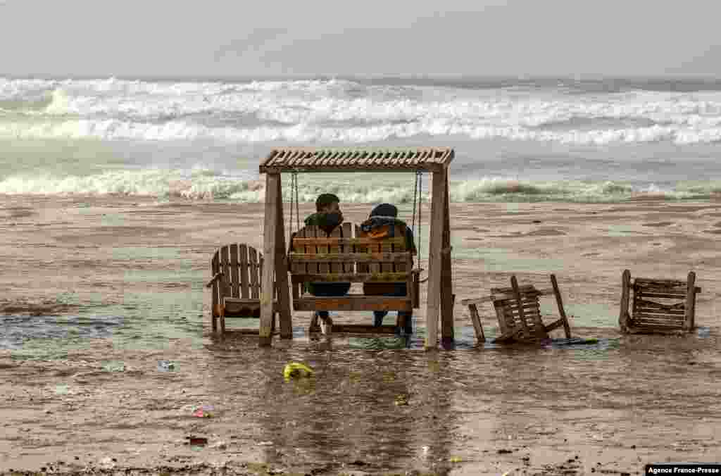 A couple sits on a swing during stormy weather on a beach by the Mediterranean Sea in Gaza City.