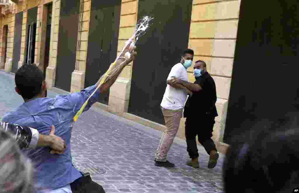 A bank customer throws eggs toward the guards of a bank, during a protest in Beirut, demanding that they be allowed to withdraw their deposits that have been blocked amid Lebanon&#39;s severe financial and economic crisis.&nbsp;