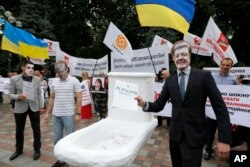 FILE - Anti-corruption activists hold a rally outside parliament in Kyiv, Ukraine, June 15, 2015. The rally organizers put a toilet seat on display as a symbol of what they felt was the effort by top officials to flush away politically inconvenient corruption cases.