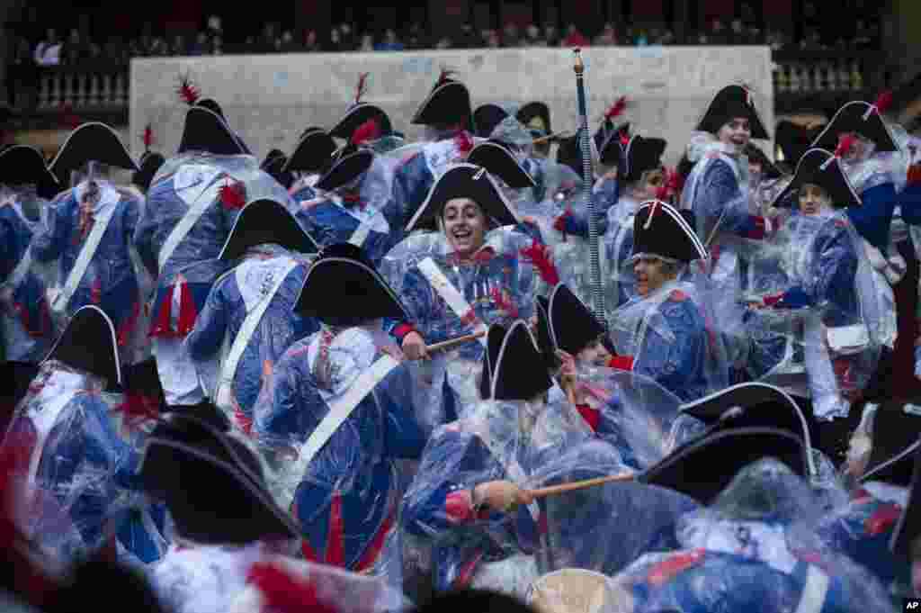 Tamborilleros wearing their uniforms try to shelter from the rain, as they march in the traditional &#39; La Tamborrada&#39;, during &#39;El Dia Grande&#39;, the main day of San Sebastian feasts, in the Basque city of San Sebastian, northern Spain. 