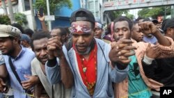 A Papuan activist with his forehead painted with banned separatist flag the "Morning Star" marches with others during a rally commemorating the 57th anniversary of the failed efforts by Papuan tribal chiefs to declare independence from Dutch colonial rule, in Surabaya, East Java.