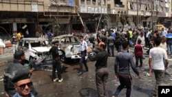 Civilians and security forces inspect the scene of a car bomb explosion in Karrada neighborhood, Baghdad, Iraq, May 9, 2015. 