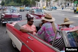 U.S. cruise ship tourists Aloyosius Howard and Kenyatta Puckett talk to a tour guide as they prepare to ride in a vintage car in Havana, Cuba, June 5, 2019.