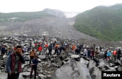 FILE - People search for survivors at the site of a landslide that destroyed 40 households, where more than 100 people were feared to be buried, in Xinmo Village, Sichuan province, China, June 24, 2017.