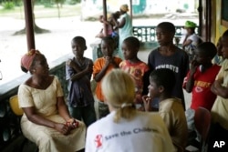 Carolyn Miles (foreground), CEO of Save the Children, listens to orphans at a Liberian government-run facility in Unification town, Oct. 3, 2014.