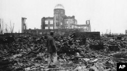 Seorang koresponden perang Sekutu berdiri di tengah puing-puing Kota Hiroshima, Jepang, pada 1945, beberapa minggu setelah bom atom meluluhlantakan kota itu. (Foto: AP)