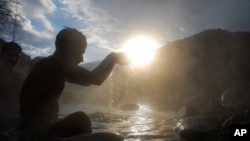 FILE - A Hindu devote offers prayers during a holy bath on the auspicious Makar Sankranti day at a natural hot water spring in Tattapani, about 52 kilometers (33 miles) north of Shimla, India.