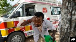 FILE - Jitendra Kumar, a paramedic who travels in ambulance, washes his face with water to cool himself off after dropping a patient at Lalitpur district hospital, in Banpur, in Indian state of Uttar Pradesh, Saturday, June 17, 2023.