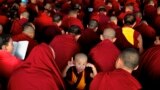 A novice Tibetan monk gestures to the camera as the spiritual leader the Dalai Lama delivers the Jangchup Lamrim teachings at the Sera Monastery in Bylakuppe, 135 miles west of Bangalore, India. 