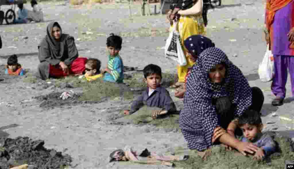 Pakistani mothers bury their children in mud during the solar eclipse in Karachi, Pakistan on Tuesday, Jan. 4, 2011. Superstitious people hope that burying ailing person during solar eclipse will cure them. (AP Photo/Fareed Khan)