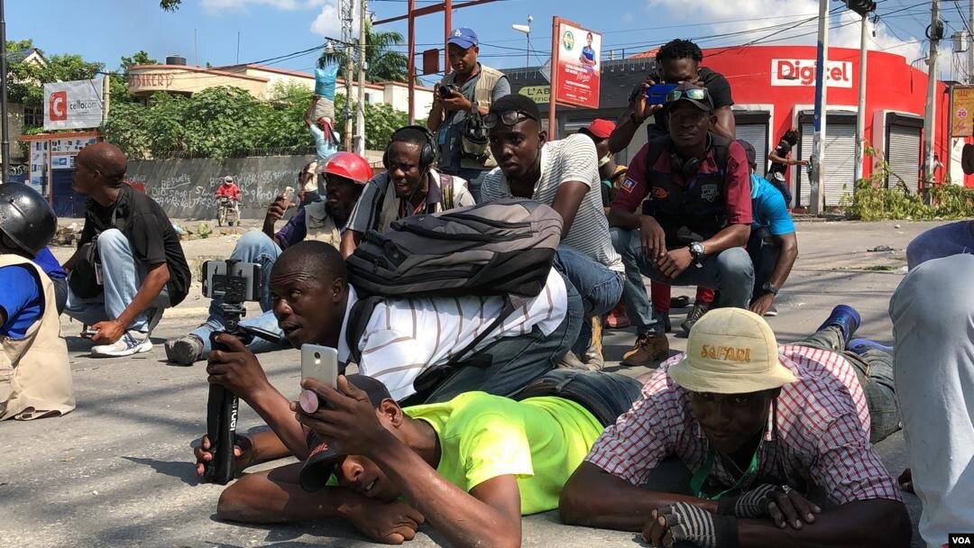 Para jurnalis Haiti bertiarap untuk menghindari terkena tembakan pada saat bentrokan antara polisi dan demonstran anti pemerintah di Port-au-Prince, Haiti, Kamis (31/10). 