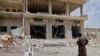 FILE - A man stares at a building damaged during reported shelling by government and allied forces, in the town of Hbeit in the southern countryside of the rebel-held Idlib province, May 3,2019. 