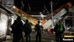 Soldiers stand as rescuers work at a site where an overpass for a metro partially collapsed with train cars on it at Olivos station in Mexico City, Mexico, May 4, 2021. 