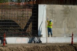 Seorang pekerja konstruksi mengecat bagian tembok perbatasan di Mission, Texas, 16 November 2020. (Foto: dok).