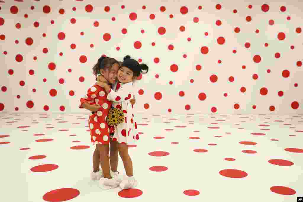 Wearing matching dresses, Takara Thomas, 3, left, and Noemi Vega, 4, hug in a polka-dotted room created by Japanese artist Yayoi Kusama, part of the installation called &quot;With All My Love for the Tulips, I Pray Forever&quot; at the Marciano Art Foundation in Los Angeles.&nbsp;