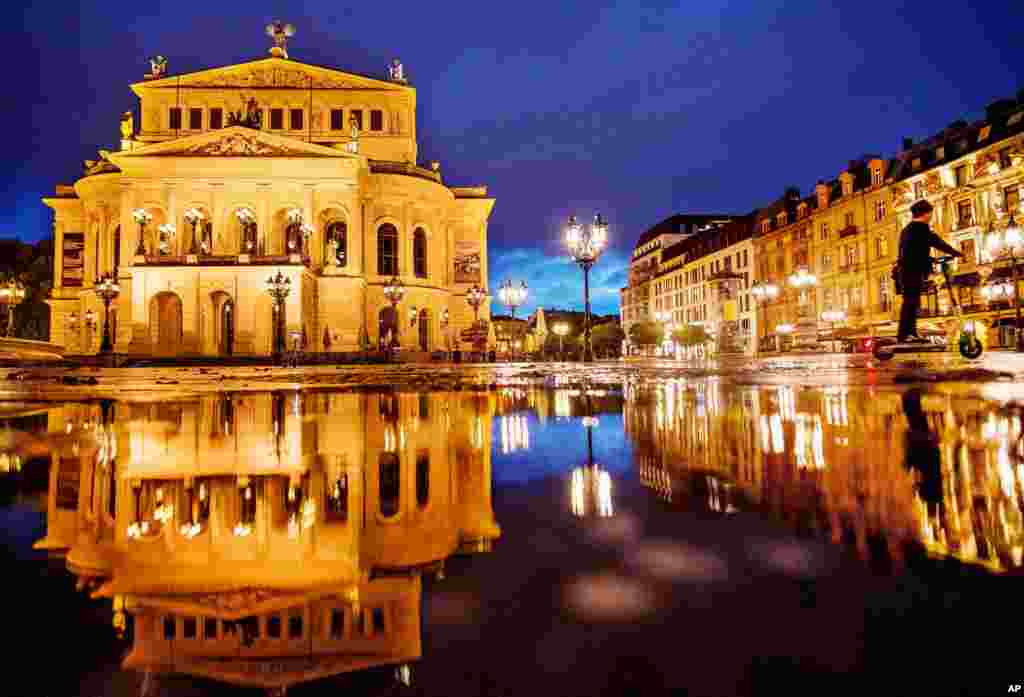 A Chinese tourist drives an E-scooter over the square in front of the Old Opera in Frankfurt, Germany.