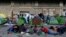 Refugees and migrants sit outside their tents at the Athens' port of Piraeus on March 10, 2016.
