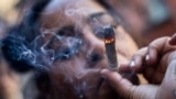 FILE - A person smokes cannabis outside the Smacked "pop up" cannabis dispensary location, Tuesday, Jan. 24, 2023, in New York. (AP Photo/John Minchillo)