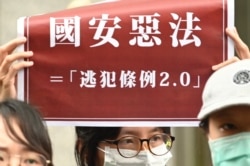 FILE - Students from Hong Kong and Taiwan display placards reading “Bad laws of China’s national security" during a protest outside the Hong Kong’s Taipei office on May 28, 2020.