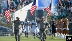 Military personnel lead the Jacksonville Jaguars players onto the field during player introductions before an NFL football game against the Miami Dolphins in Jacksonville, Florida, Sept. 20, 2015.