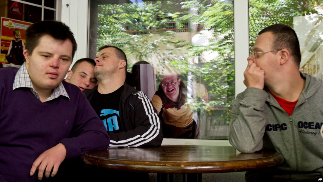 FILE - Customers and employees shown outside a coffee shop, run by employees affected with Down Syndrome in Pristina, Kosovo.