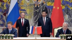 Russia's President Vladimir Putin (Background L) and China's President Xi Jinping (Background R) watch during a signing ceremony in Shanghai, China, May 21, 2014.