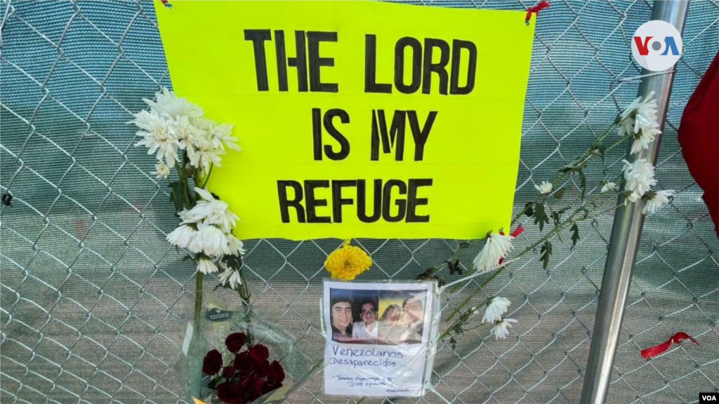 Un cartel con una plegaria y fotograf&#237;as de quienes identifican como venezolanos desaparecidos se ve en la cerca que limita el paso al &#225;rea del edificio colapsado. 