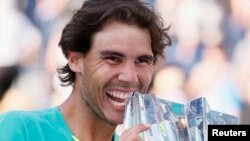 Rafael Nadal dari Spanyol berpose dengan pialanya setelah mengalahkan Juan Martin Del Potro dari Argentina dalam final tunggal putra BNP Paribas Terbuka, Minggu (17/3). (Reuters/Danny Moloshok)