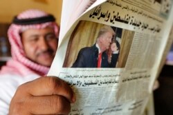 FILE - A man holds the daily Asharq Al-Awsat newspaper fronted by a picture of U.S. President Donald Trump, at a coffee shop in Jiddah, Saudi Arabia, Jan. 29, 2020, following Trump's unveiling of a Mideast peace plan.