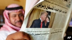A man holds the daily Asharq Al-Awsat newspaper fronted by a picture of U.S.President Donald Trump, at a coffee shop in Jiddah, Saudi Arabia, Jan. 29, 2020, following Trump's unveiling of a Mideast peace plan. 