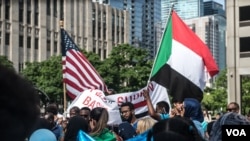 Protesters hold American and Sudanese flags at a rally in support of the Sudan's revolution, in Chicago, Illinois, June 29, 2019. (J. Patinkin/VOA)