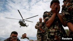 Soldados nepaleses se cubren mientras un helicóptero de la India evacúa personas heridas en Sindhupalchowk, luego del terremoto del sábado.