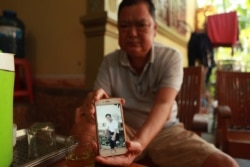 Nguyen Thanh Le holds a photo of his son Nguyen Van Hung, Oct. 28, 2019, in Dien Chau district, Nghe An province, Vietnam.