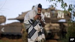 FILE - An Israeli soldier prays in front of a tank at a staging area near Israel's border with the Gaza Strip, in southern Israel, Dec. 30, 2008.