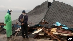 Warga melihat bangunan yang rusak di Ambon, Maluku, 27 September 2019. (Foto: AP)