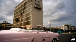 Tourists take a ride in a vintage car as they pass the U.S. embassy in Havana, Cuba, March 18, 2019. 