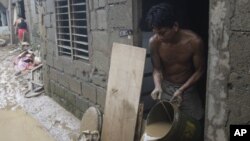 Ramon Fabros pours muddy water out of his house after floodwaters brought by Typhoon Nesat receded, September 28, 2011 in suburban San Mateo, eastern of Manila, Philippines.