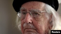 FILE - Nicaraguan poet, priest and Reina Sofia Prize winner, Ernesto Cardenal, who according to local media is being charged for damages against former Tourism Minister Nubia Arcia, listens to his assistant during a meeting at his house in Managua, Nicaragua, Feb. 16, 2017.