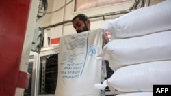 A Palestinian worker empties sacks of flour donated by the World Food Programme at a bakery in Gaza City on April 14, 2024, amid the ongoing conflict between Israel and the militant group Hamas.