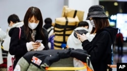 FILE - Travelers from Beijing, wearing masks, arrive at Charles de Gaulle airport in France, Jan. 27, 2020. Members of the East Asia community say the coronavirus, which originated in China, is giving rise to latent racism.